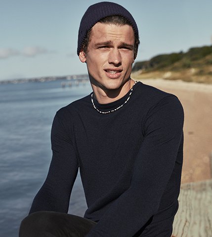 Man on beach in navy crewneck sweater